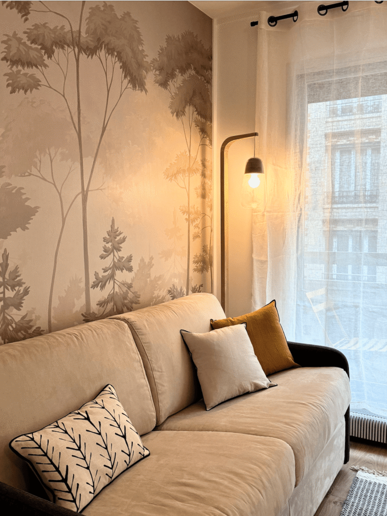Salon du studio parisien au Trocadéro avec canapé beige et papier peint végétal