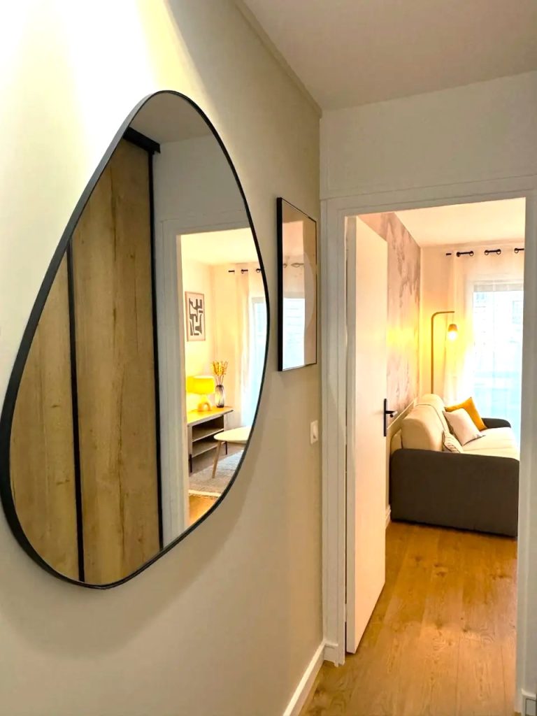 Entrée rénovée avec grand miroir mural dans un appartement parisien